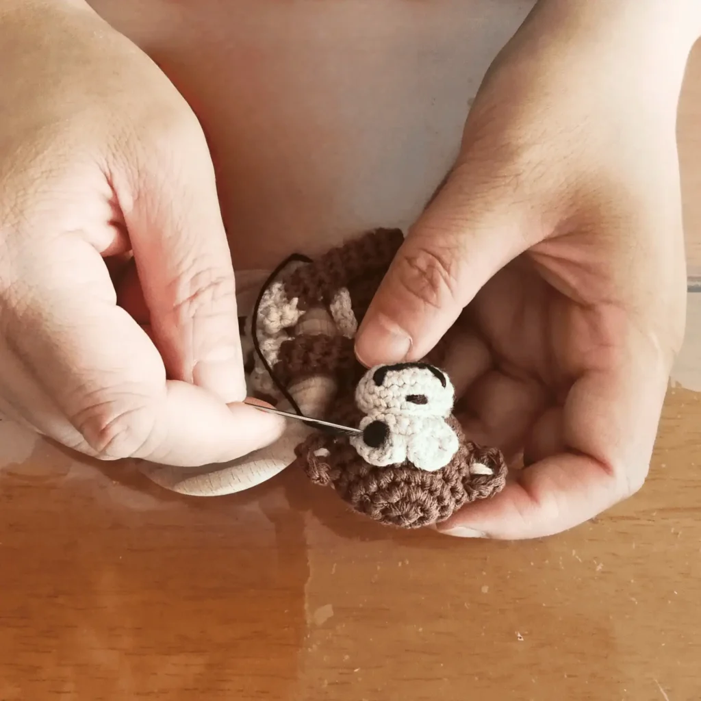 Aufsticken der Augen per Hand auf den Hänge-Greifling Affe CHARLIE, Detailaufnahme der handwerklichen Verarbeitung