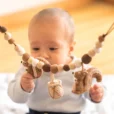 Baby greift nach einem der gehäkelten Eichhörnchen der Kinderwagenkette.