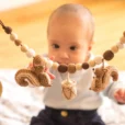 Baby betrachtet die gehäkelte Kinderwagenkette mit neugierigem Blick.