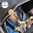 Holzclip mit SindiBaba-Logo im Kinderwagen, Baby schaut auf die gehäkelte Kette.