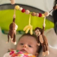 Baby im Kinderwagen blickt schräg nach oben zur gehäkelten Kinderwagenkette Affe CHARLIE