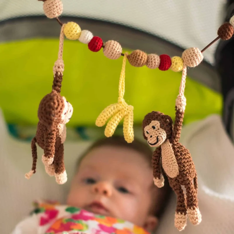 12625-stroller-chain-monkey-lifestyle-baby-stroller-1 Baby im Kinderwagen blickt schräg nach oben zur gehäkelten Kinderwagenkette Affe CHARLIE