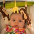 Nahaufnahme der gehäkelten Kinderwagenkette Affe CHARLIE am Kinderwagen mit Baby