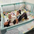 Mutter mit Zwillingen im Laufstall mit Spielbogen und SindiBaba® Spielzeug
