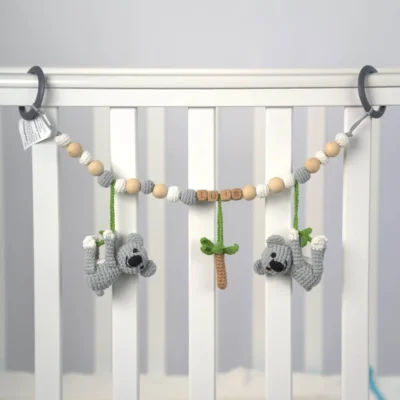 Personalisierte Kinderwagenkette mit Koala-Motiv und Namen Luis am Kinderbett befestigt.
