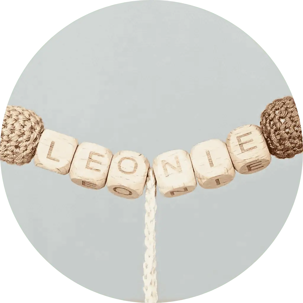 Detailansicht der Namenspersonalisierung mit Buchstaben-Holzwürfeln auf einer SindiBaba Kinderwagenkette.