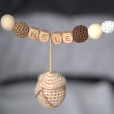 Detailaufnahme: personalisierte Kinderwagenkette mit Reh/Nuss-Motiv und Namen Nele