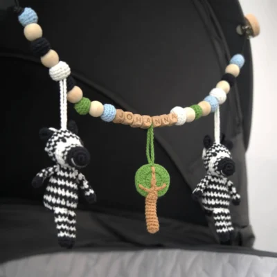 Personalisierte Kinderwagenkette mit Zebra-Motiv und Namen Johanna am Kinderwagen befestigt.